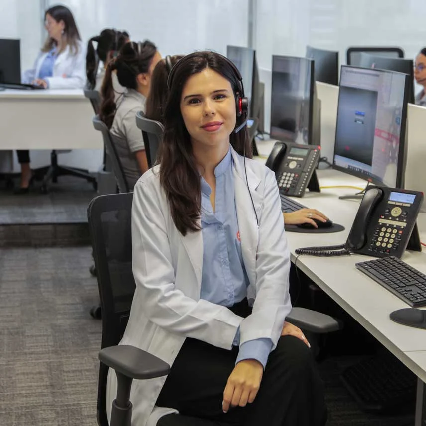 Uma atendente da Telehelp sorrindo e sentada na Central de Atendimento.