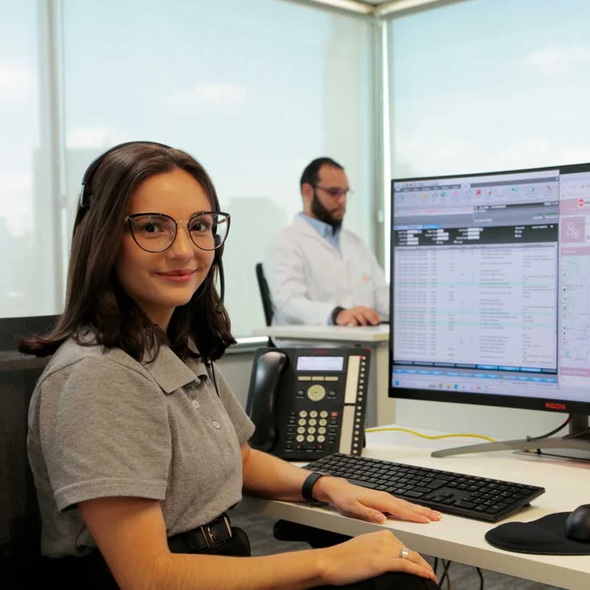 Uma atendente TeleHelp sorrindo sentada na central de atendimento.